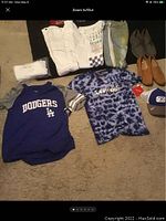 Photo showing various men's clothing and footwear items including Dodgers shirt, Savage shirt, pants, shoes, and baseball caps.