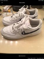 Side view of Nike Air Force 1 GS white sneakers showing detailed swoosh design and general condition.