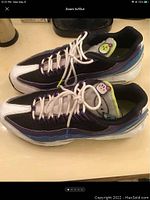 Pair of Nike Air Max 95 sneakers sitting side by side on a beige surface, showing right side profile with multicolor panels and white laces.