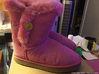 Pink Ugg boots shown from front and side angles highlighting the fur lining and signature button detail.