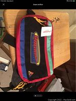 Front view of the Pyramid multicolored fanny pack showing brand logo and yellow zipper pulls on red, black, blue, and green panels.