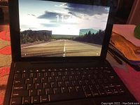 Tablet powered on with road wallpaper and time 11:46, connected to keyboard