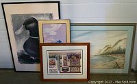 Four framed art pieces grouped together including a duck painting, Asian print, large landscape, and street scene print.