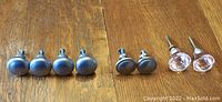 Photo showing eight drawer pulls with four silver round knobs, two silver oval knobs, and two clear faceted knobs.