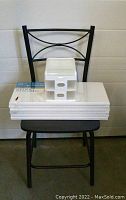 Metal chair with storage case and six canvases stacked on seat