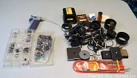 Image overview of the photographic accessories lot showing shutter release handles, cables, film spools, lens adapters, small parts organized in plastic trays, and a sealed flexible shutter release cable pack.