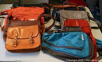 Photo showing 5 various purses and bags in mixed colors including orange, tan, blue, and red.