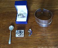 Photo of sterling silver rings, pendant, brooch, small spoon, and cuff bracelet