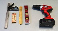Full view of power drill, carpenter's ruler, level tool, combination square, and router bit.