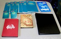 All notebooks and pads laid out showing variety and quantity, including red elephant notebook, floral patterned notebook, large black notebook, seven blue steno pads and two smaller blue and white notepads.