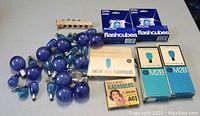 Wide view of collection showing loose vintage flashbulbs scattered with three boxed flashbulb products including Philips Flashcubes.