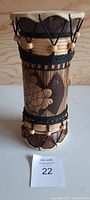 Front view of handcrafted wooden drum showing decorated carved wood and rope fastening