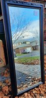 Full view of the large rectangular mirror reflecting outdoor scenery, showing the size and style of the frame.