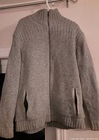 Full front view of grey wool-blend men's sweater with zipper and pockets.