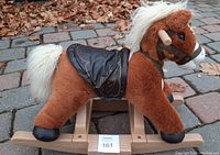 Side view showing the full plush rocking horse with wooden rocker base, black saddle, and wooden handles.