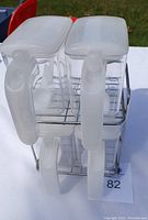 Top-down angled view of four clear plastic containers stacked in metal stand showing large handles and frosted lids