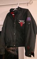 Front view of a black vintage Chicago Bulls jacket with front logo and NBA patch on sleeve.