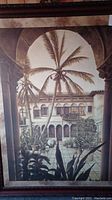 Full view of framed artwork showing the courtyard with palm trees and architectural elements in neutral tones.