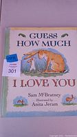 Front cover of the large hardcover book 'Guess How Much I Love You' showing the title, author Sam McBratney and illustrator Anita Jeram.