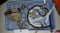 Large cuff bracelet and assorted necklaces in blue ceramic dish