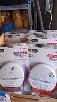 Photo showing combination Smoke + Carbon Monoxide Alarm and four Smoke Alarms in packaging
