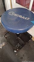 Top view of round blue Kobalt padded seat showing wear and stains.
