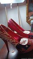 Pair of red custom painted high heels with New England Patriots logo and handwritten detailing on the heel and sides