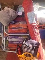 Photo of Tommy Bahama backpack chair with multicolored striped fabric, a small black and white Igloo cooler, red water bottle in an orange plastic caddy, and red Tommy Bahama umbrella carrying bag.