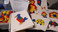 Photo showing colorful wooden geometric pattern blocks and instructional pages with sample pictures featuring animals and shapes.