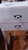 Close photo of white two-drawer sewing table showing drawer knobs and carved trim detail