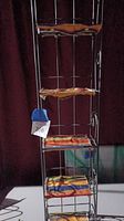 Full view of the six-shelf tall and skinny gray metal wire rack showing fabric covers on each shelf