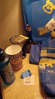 Overview of vintage UCLA items including blue water bottle, paper cup, plastic container with UCLA logo, blue cobalt glass bottle, and vintage T-shirts.