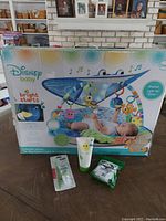 Photo of the Disney Baby Finding Nemo Bright Starts gym box with baby items in front including sunscreen lotion, teething mitt, and toothpaste.