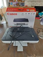 Canon PIXMA MG3022 printer with USB cable on table with box behind