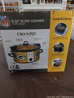 Box of Green Bay Packers branded Crock-Pot slow cooker showing front and side panel with key features and team design.