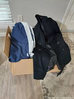Box containing navy and white swim shorts and black coat.