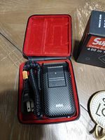 Braun electric shaver open in its black leather case with red interior lining, coiled power cord visible.