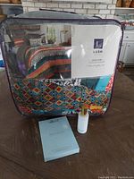 Packaged Lush Décor 7 piece King Comforter set with colorful boho stripe pattern, silk pillow sleeve box, and white room spray bottle on table.
