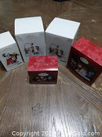 Five boxed Peanuts Hallmark Christmas ornaments shown from front angle on wooden floor.