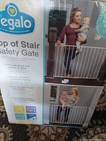 Front of box showing a woman and baby using the Regalo baby gate at the top of stairs.