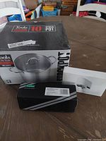 Photo of the boxed 10 quart stock pot, sink drain stopper, and water saving tap on a table.