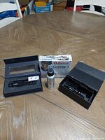 Full lot on table including laser tool, red dot sight box, flashlight box, and mosquito repellent can