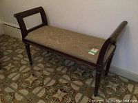 Front angled view of wooden bench showing fabric upholstered seat and the armrest design.