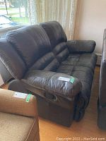 Full side view of brown leather two-seat couch with recliner lever on the side, showing overall shape, padding, and condition.