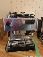 Front view of the Faema Farma coffee machine showing control panel with switches, rotary knob, and steam wand.