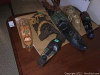 Photo of six wooden masks laid out on cardboard, showing shapes, colors, and sizes