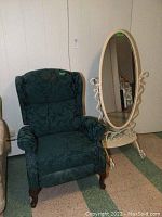 Green floral upholstered chair and white oval full-length stand mirror