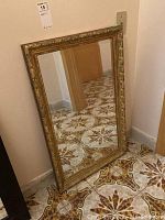 Full view of the rectangular mirror leaning against a wall showing its size and design.