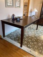 Wooden rectangular dining table with dark finish, tapered legs, and some decorative items on top.