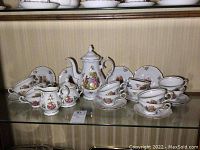 Full view of Winterling tea set including teapot, cups, and saucers arranged on glass shelf
